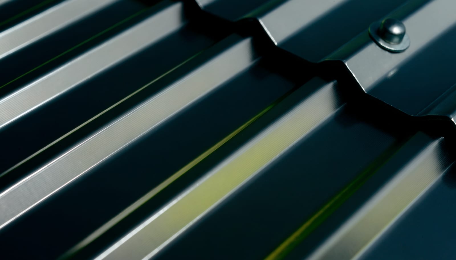 Close-up of the ribbed profile of a galvanized steel panel with a bolted fastener